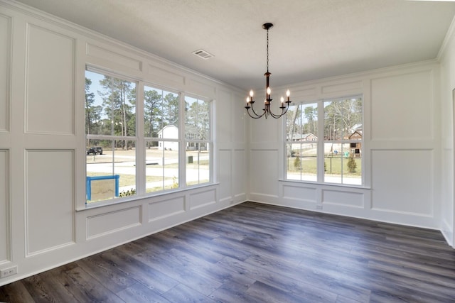 unfurnished dining area with visible vents, dark wood-style flooring, crown molding, a decorative wall, and a chandelier