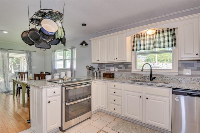 3114 Sussex Rd, Augusta, GA 30909 - kitchen with appliances with stainless steel finishes, a peninsula, healthy amount of natural light, white cabinetry, and ornamental molding