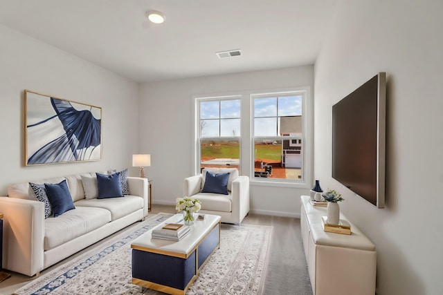 living area featuring baseboards, visible vents, and light carpet