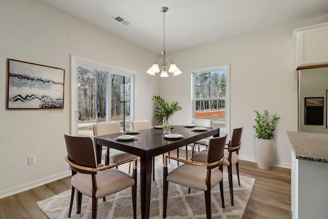 dining room with baseboards, light wood-style floors, visible vents, and a chandelier