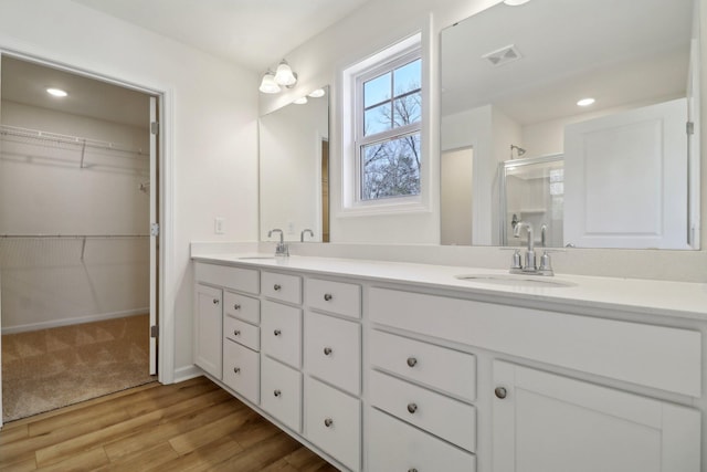 bathroom featuring a shower stall, double vanity, visible vents, and a sink