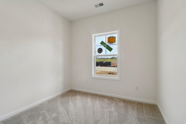 carpeted spare room with visible vents and baseboards