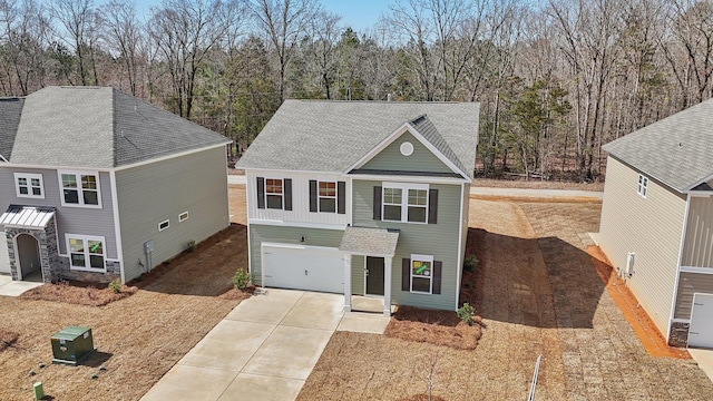 view of front facade with driveway, a shingled roof, and an attached garage