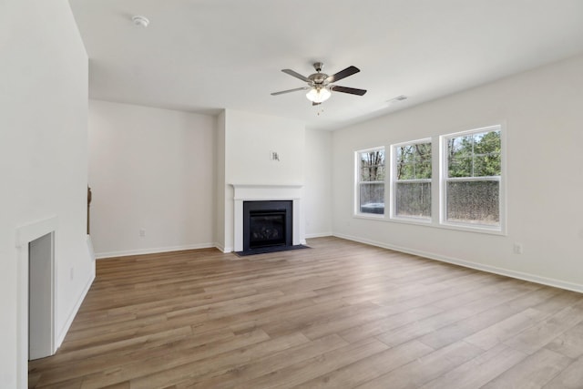 unfurnished living room featuring visible vents, a fireplace with flush hearth, a ceiling fan, light wood finished floors, and baseboards