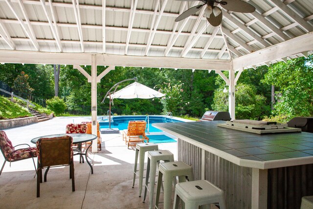 view of swimming pool featuring exterior bar, a gazebo, ceiling fan, and a patio area