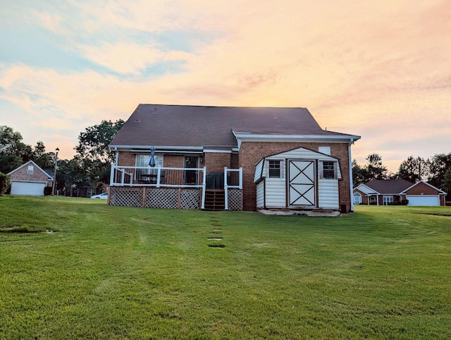 rear view of house with brick siding, a yard, and a deck