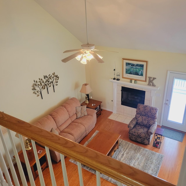 living area featuring a fireplace, wood finished floors, lofted ceiling, and ceiling fan