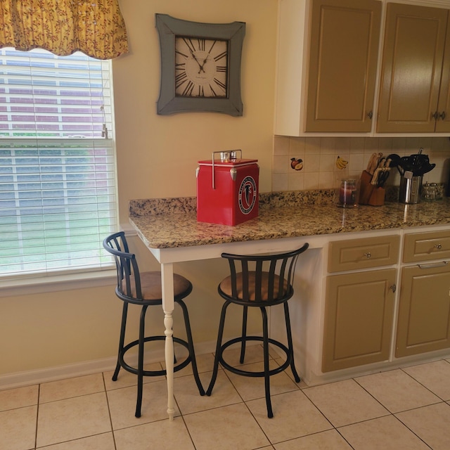 kitchen featuring light tile patterned floors, a kitchen breakfast bar, and baseboards