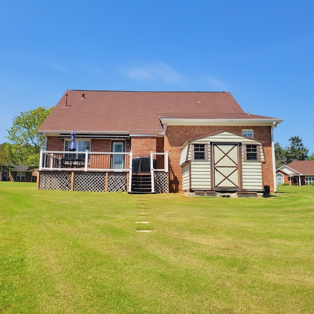 rear view of property featuring brick siding, a lawn, and a wooden deck