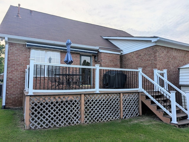 rear view of property featuring brick siding and a deck