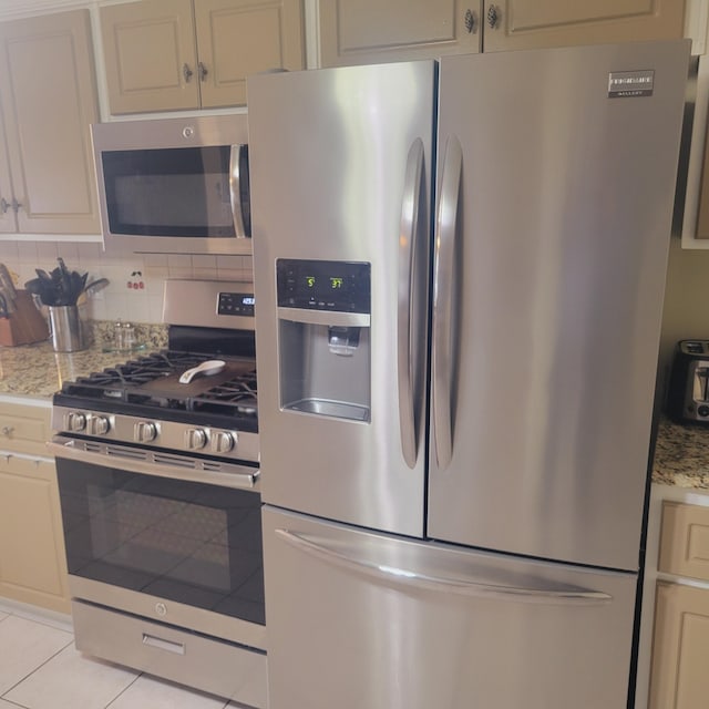 kitchen featuring stainless steel appliances, light tile patterned floors, and backsplash