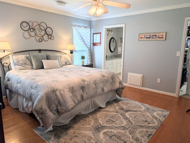 bedroom featuring ornamental molding, wood finished floors, baseboards, ensuite bathroom, and ceiling fan