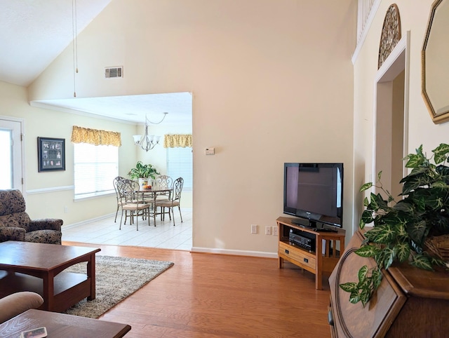 living room with light wood-style floors, high vaulted ceiling, baseboards, and a chandelier