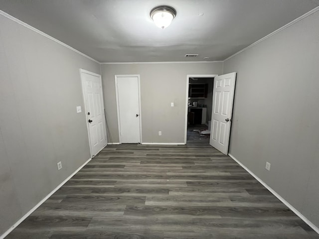 empty room with dark hardwood / wood-style flooring and crown molding