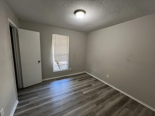 empty room with dark wood-type flooring and a textured ceiling