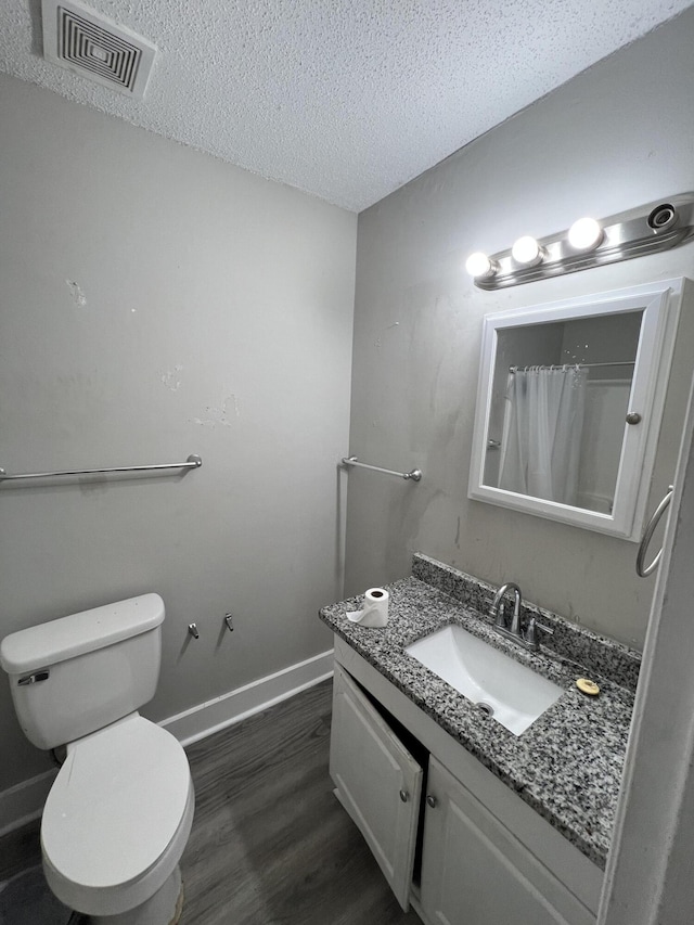 bathroom featuring a shower with shower curtain, vanity, a textured ceiling, hardwood / wood-style flooring, and toilet