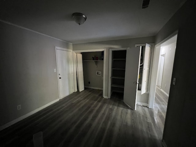 unfurnished bedroom featuring dark wood-type flooring and two closets