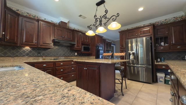 kitchen featuring pendant lighting, a kitchen breakfast bar, crown molding, light stone countertops, and stainless steel appliances