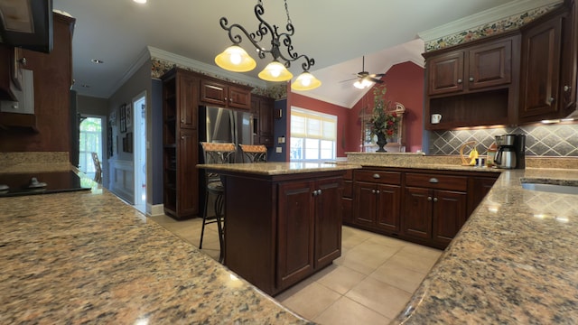 kitchen with black stovetop, vaulted ceiling, ceiling fan, decorative light fixtures, and a kitchen bar