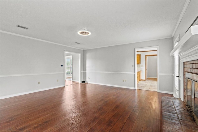 unfurnished living room featuring a textured ceiling, crown molding, visible vents, hardwood / wood-style floors, and a brick fireplace