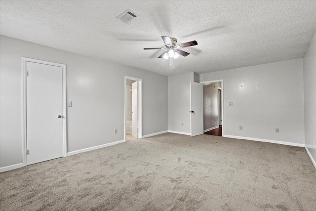 unfurnished bedroom with carpet flooring, ensuite bath, visible vents, baseboards, and a textured ceiling