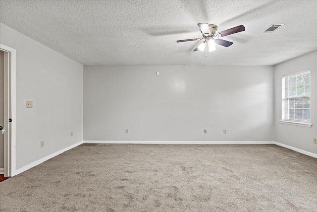 carpeted spare room featuring baseboards, visible vents, a ceiling fan, and a textured ceiling