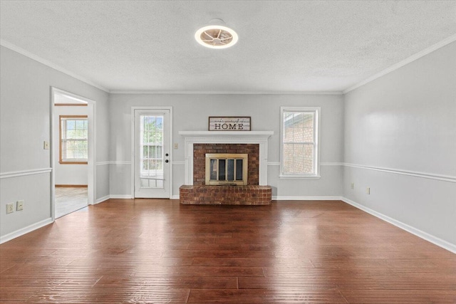 unfurnished living room with a textured ceiling, hardwood / wood-style flooring, crown molding, and baseboards