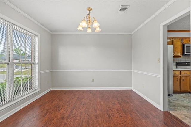 unfurnished room with a notable chandelier, visible vents, wood finished floors, and baseboards