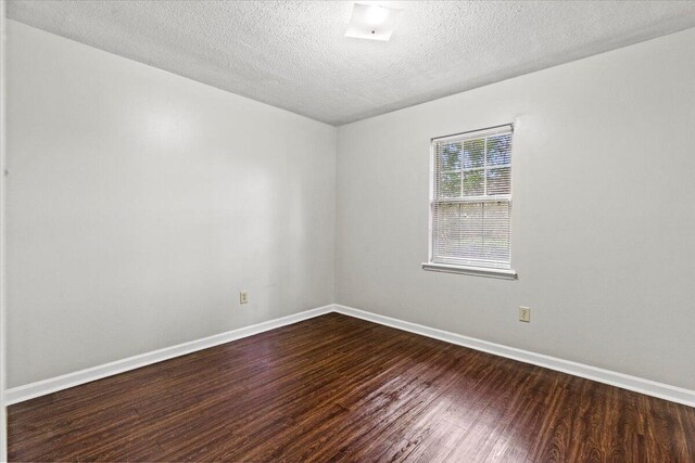empty room with baseboards, a textured ceiling, and dark wood-style flooring