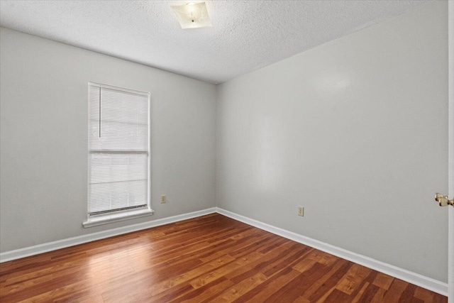 unfurnished room with baseboards, wood finished floors, and a textured ceiling