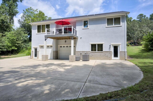 back of property featuring a balcony, cooling unit, and a garage