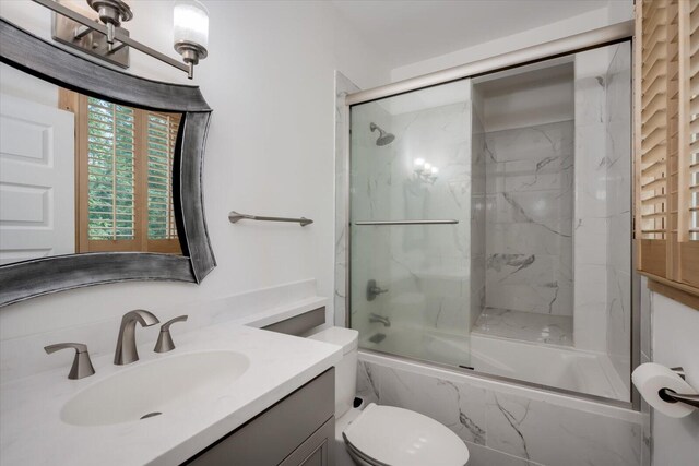 full bathroom featuring shower / bath combination with glass door, vanity, and toilet