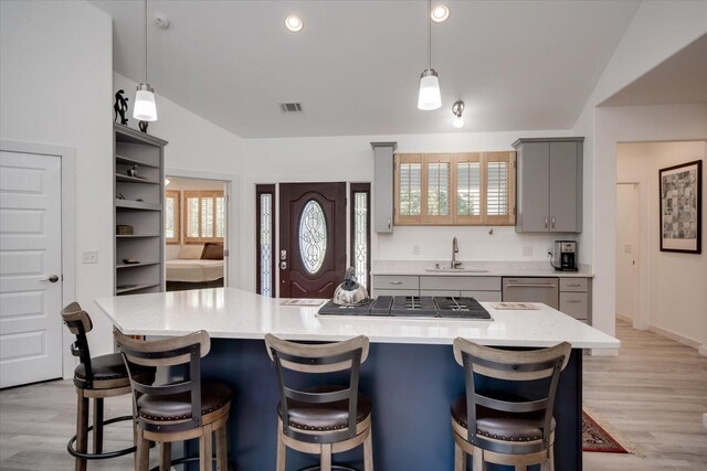 kitchen featuring gray cabinetry, sink, light hardwood / wood-style flooring, decorative light fixtures, and appliances with stainless steel finishes