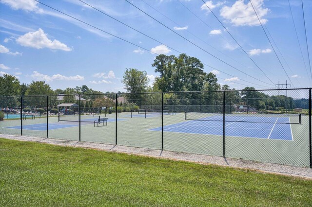 view of tennis court featuring a lawn