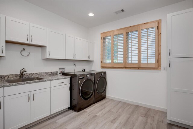 laundry area with separate washer and dryer, sink, cabinets, and light hardwood / wood-style flooring