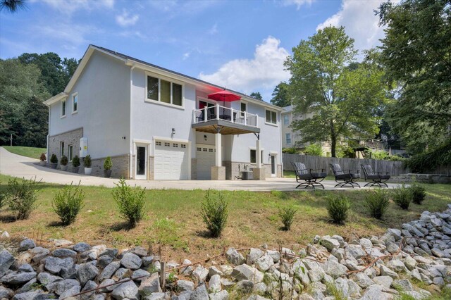 back of property with a balcony, a garage, and central air condition unit