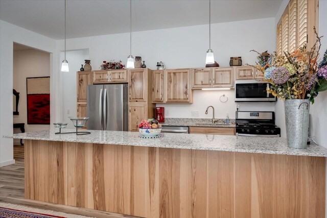 kitchen featuring sink, stainless steel appliances, light stone counters, decorative light fixtures, and light wood-type flooring