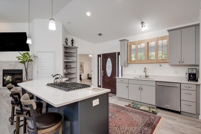 kitchen with pendant lighting, a center island, sink, vaulted ceiling, and appliances with stainless steel finishes