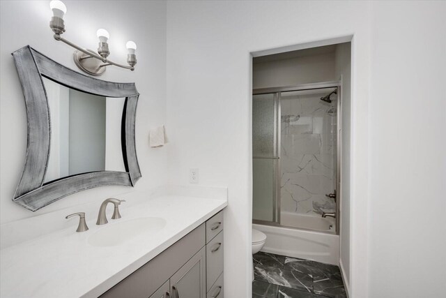 full bathroom featuring vanity, bath / shower combo with glass door, and toilet