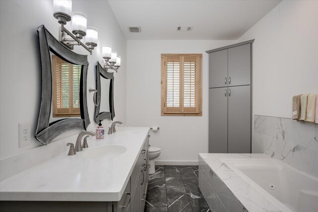 bathroom featuring vanity, a healthy amount of sunlight, toilet, and tiled bath