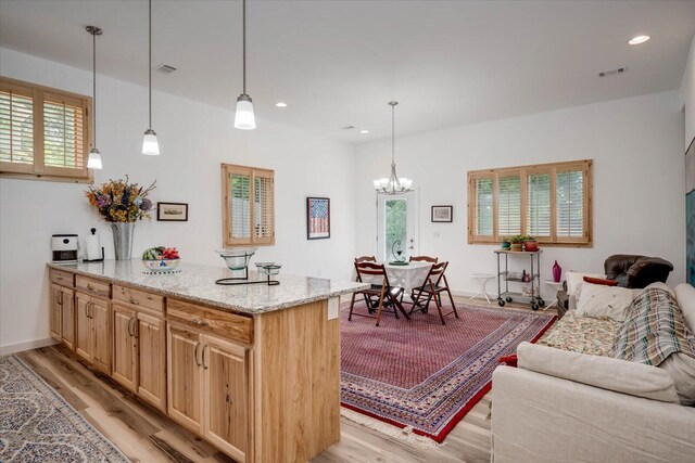 kitchen featuring a notable chandelier, decorative light fixtures, light hardwood / wood-style floors, and light stone countertops