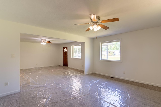 empty room featuring a ceiling fan, visible vents, and baseboards