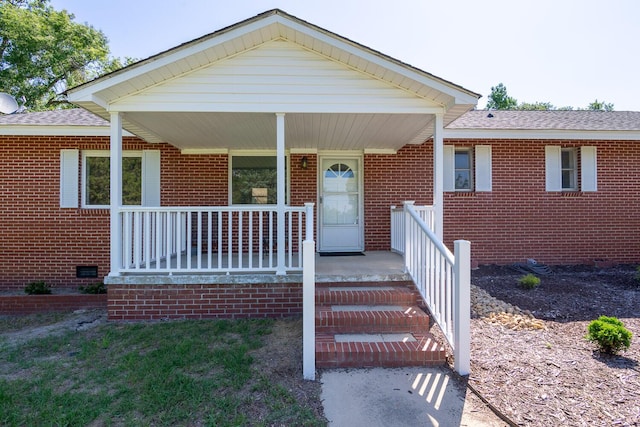 view of front of property with covered porch, brick siding, crawl space, and roof with shingles