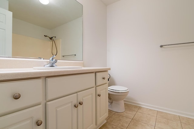 bathroom with toilet, tile patterned flooring, vanity, and baseboards
