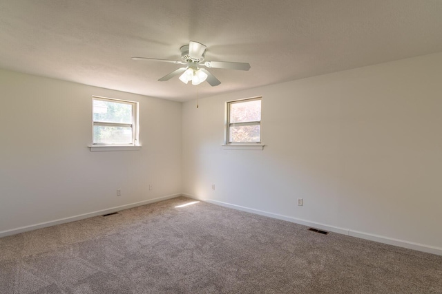 carpeted empty room featuring baseboards, visible vents, and ceiling fan