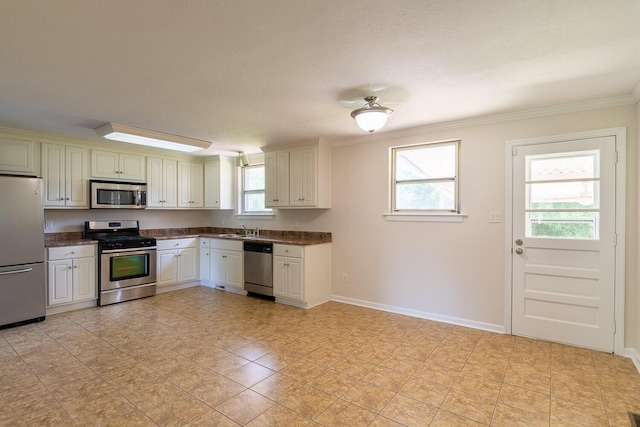 kitchen featuring ornamental molding, dark countertops, appliances with stainless steel finishes, and a sink