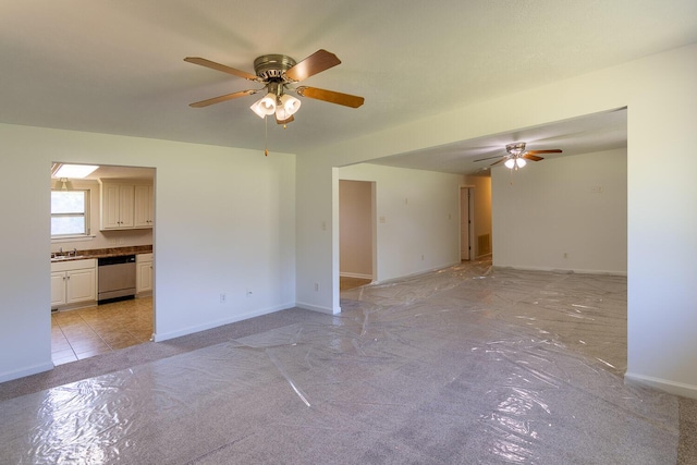 unfurnished living room featuring a sink, ceiling fan, and baseboards