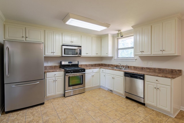 kitchen with light tile patterned floors, stainless steel appliances, dark countertops, and a sink