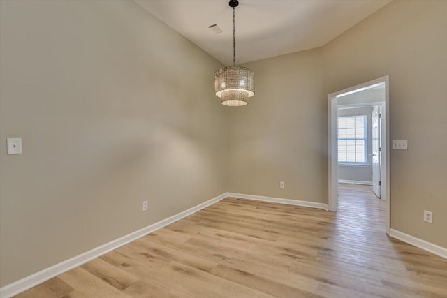 empty room featuring visible vents, baseboards, light wood-style floors, and an inviting chandelier