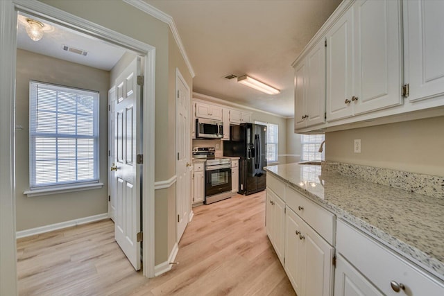 kitchen with stainless steel appliances, white cabinetry, visible vents, and light wood finished floors